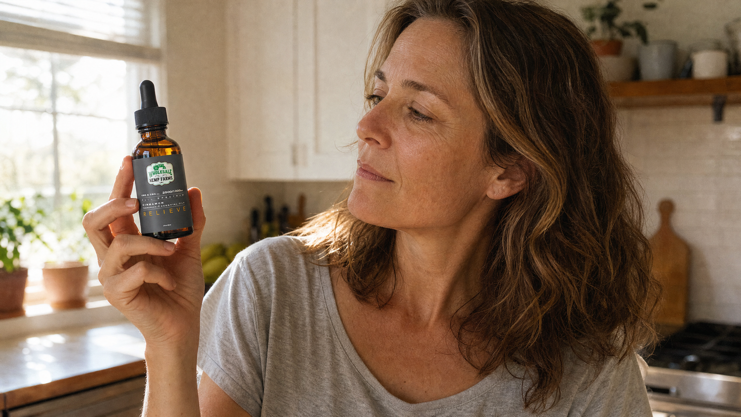 Woman in a sunlit kitchen examining a Wholesale Hemp Farms Relieve full-spectrum CBD tincture dropper
